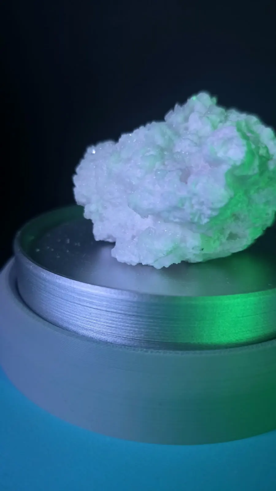 Wit kristal op een metalen sokkel onder groen licht