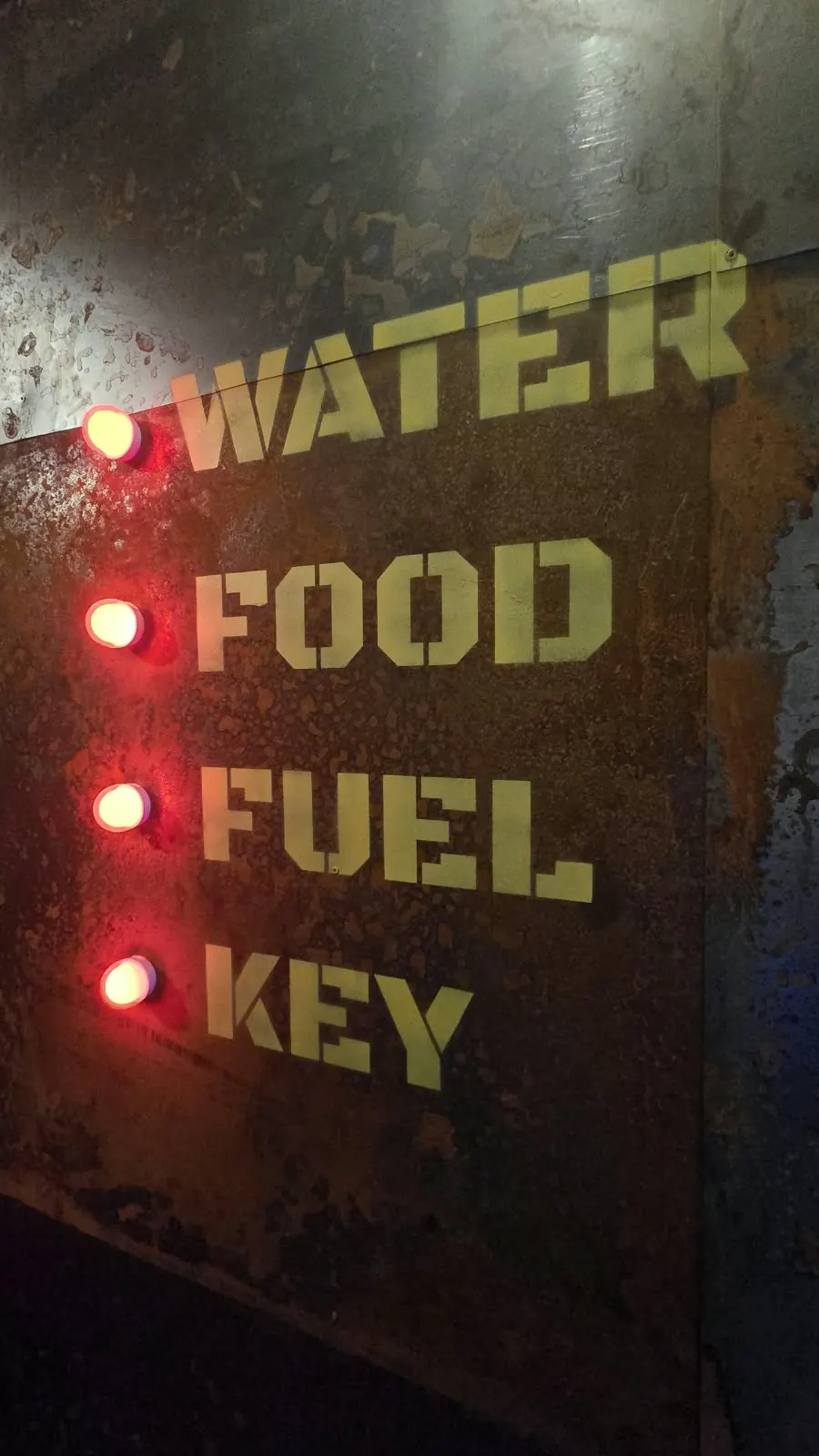 Roestig paneel met lampjes bij Water, Food, Fuel en Key